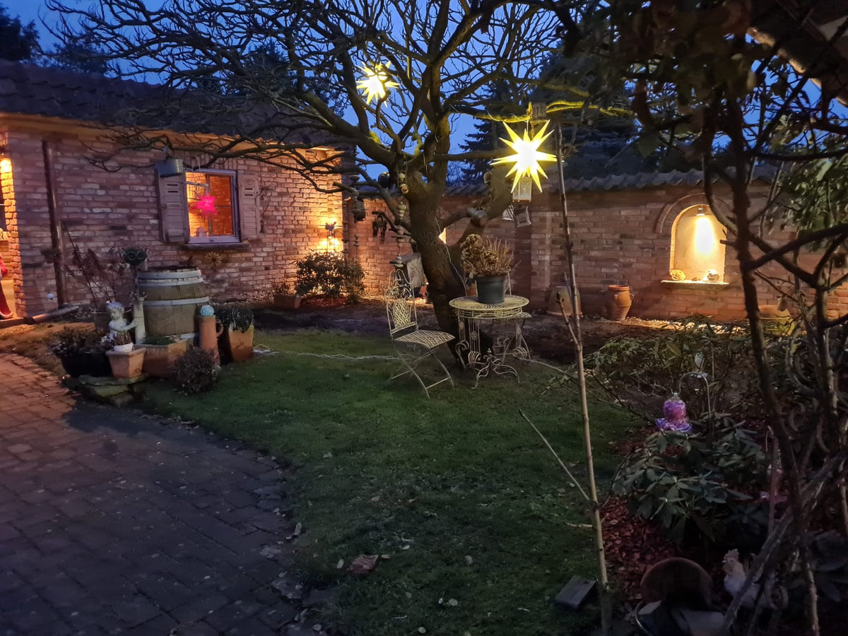 Garten am Abend mit Ziegelmauerwerk und beleuchteter Rundbogennische